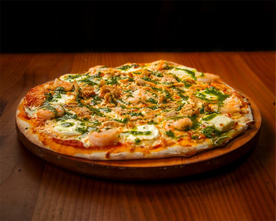 Pizza Isabella — Base pomodoro, mozzarella, camarón salteado con ajo, pollo, queso crema, ciboulette y pesto de albahaca.
